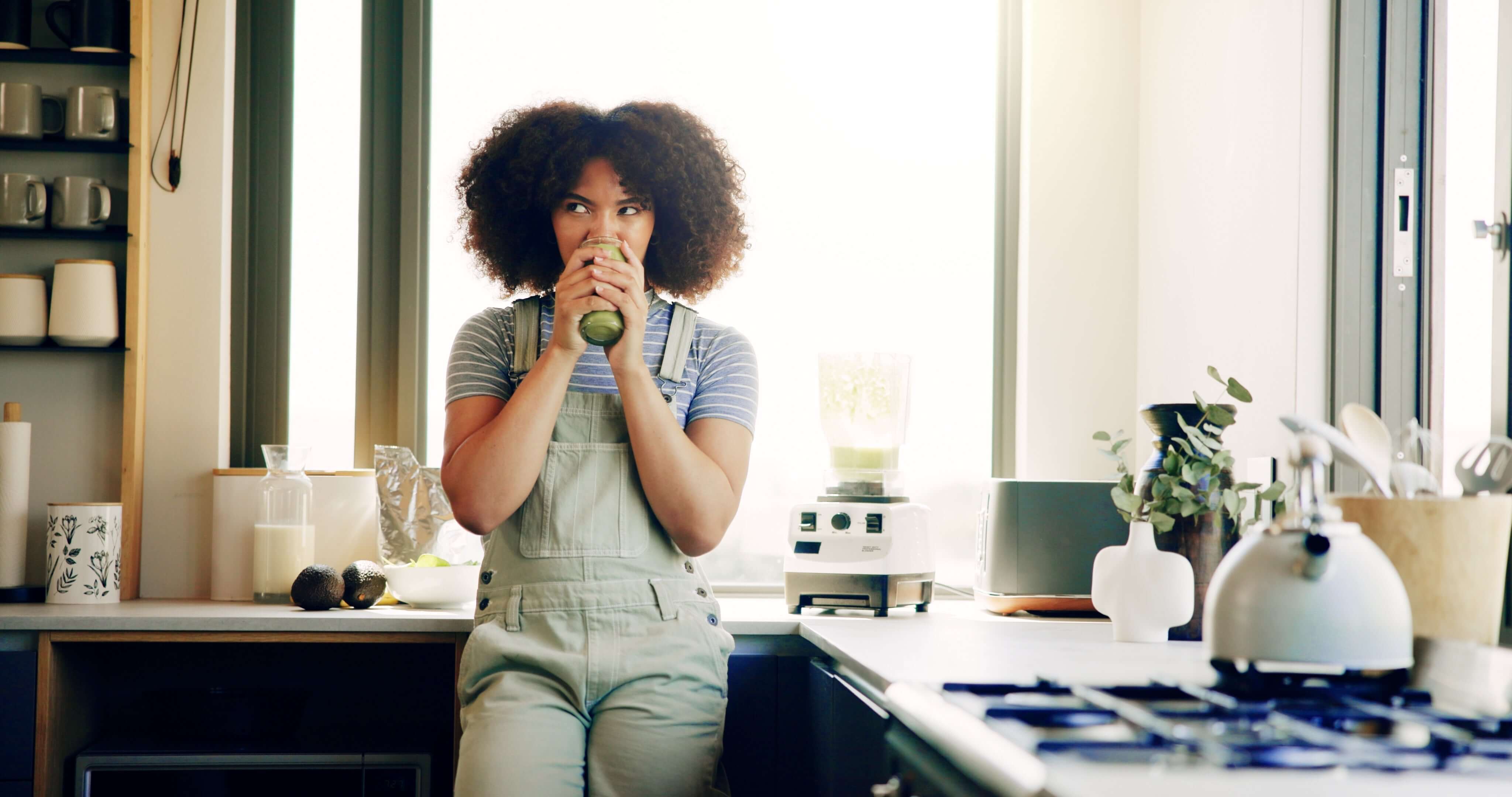 a woman at home enjoying a greens drink