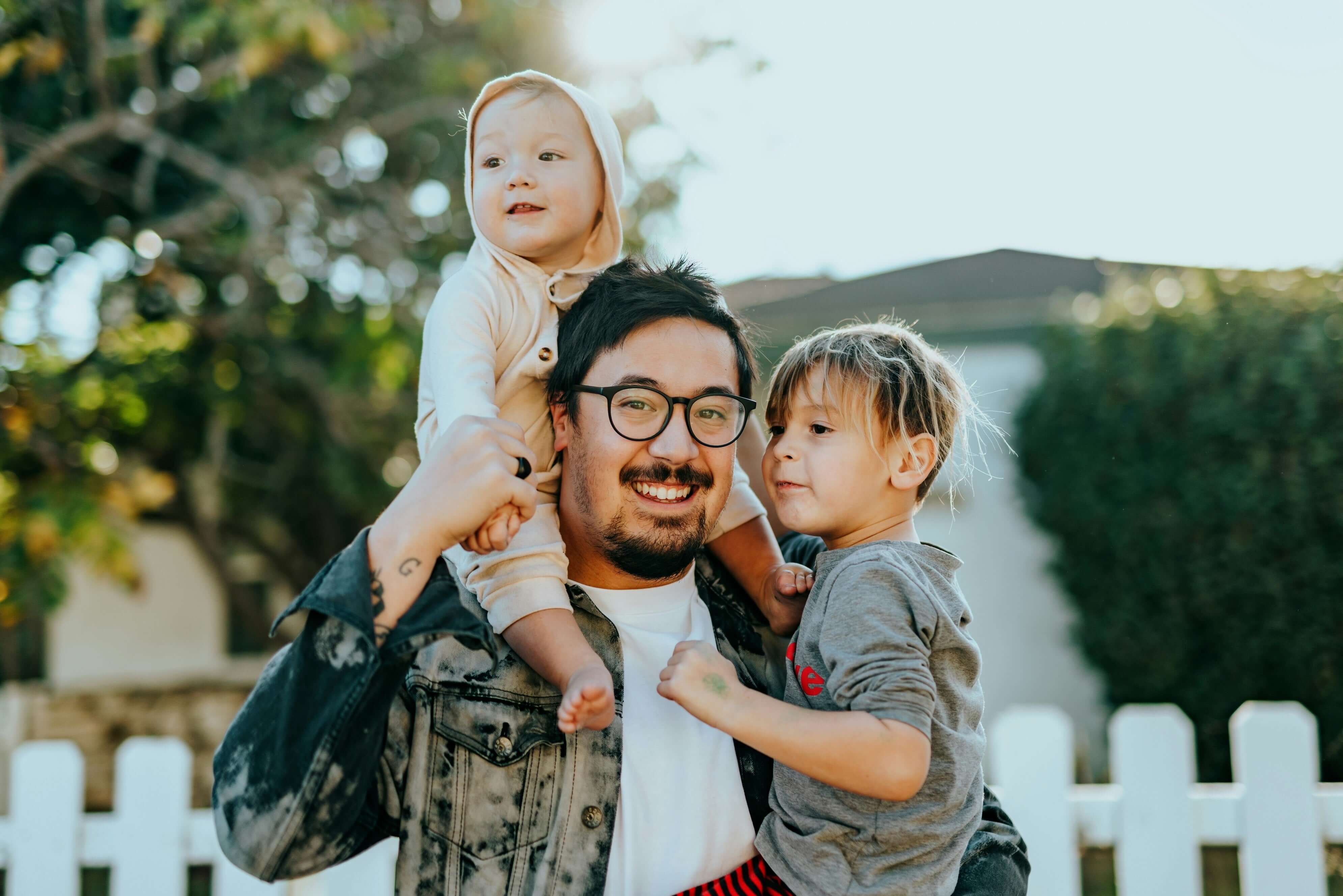 a couple outside their home with a white picket fence behind them