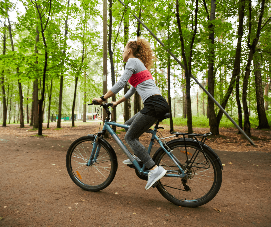 woman riding a mountain bike in the woods surrounded by tall trees