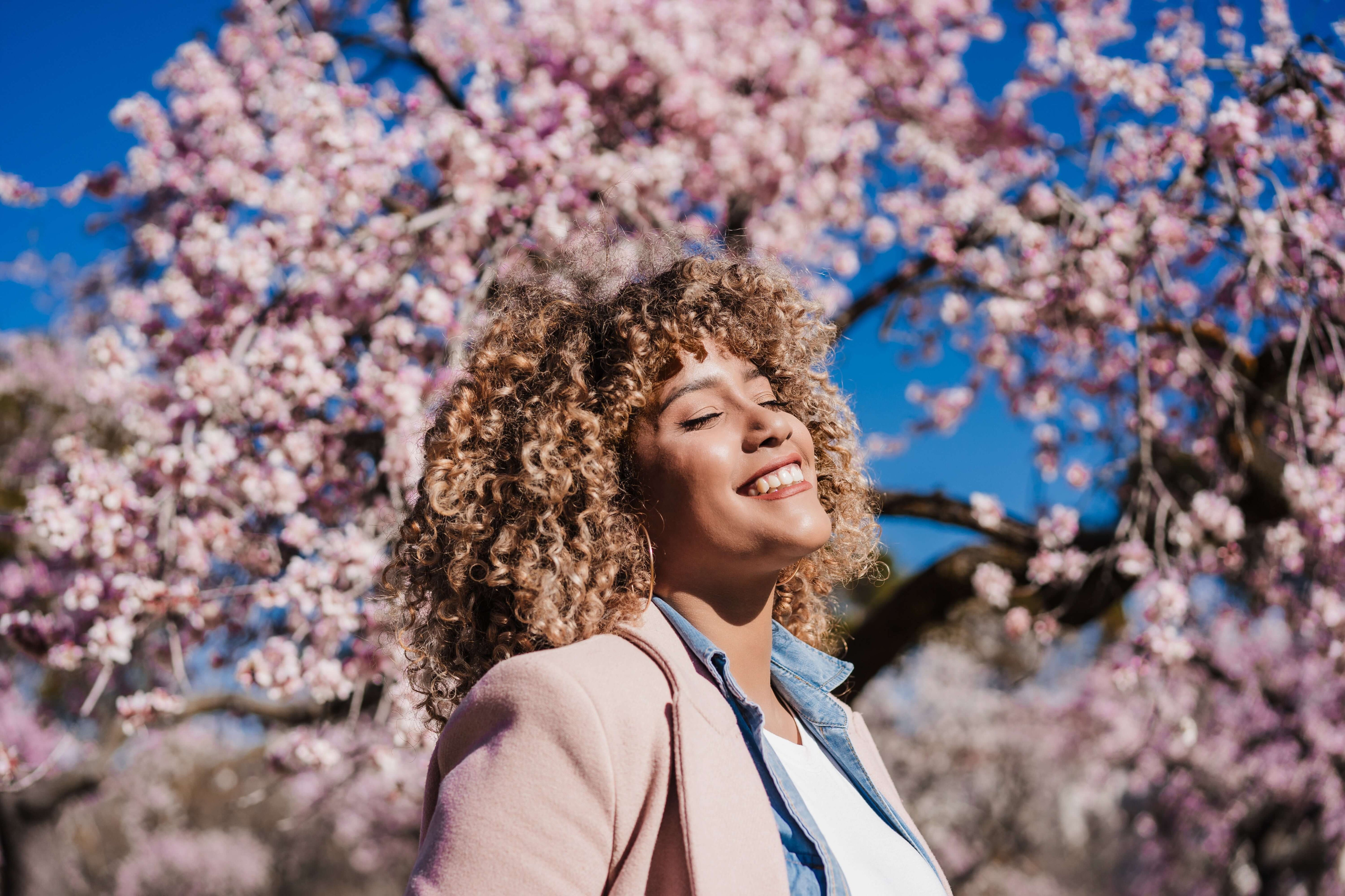 a woman outside with beautiful pink flowers behind her