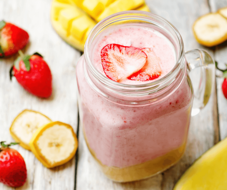 strawberry banana mango fruit smoothie featuring barlean's omega pals liquid omegas for kids with strawberry and banana and mango garnishes surrounding the mason jar