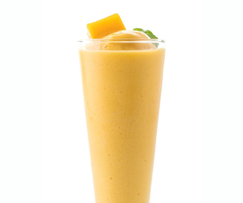 Creamy Sunshine Smoothie with Multivitamin in a tall glass topped with mango and mint.