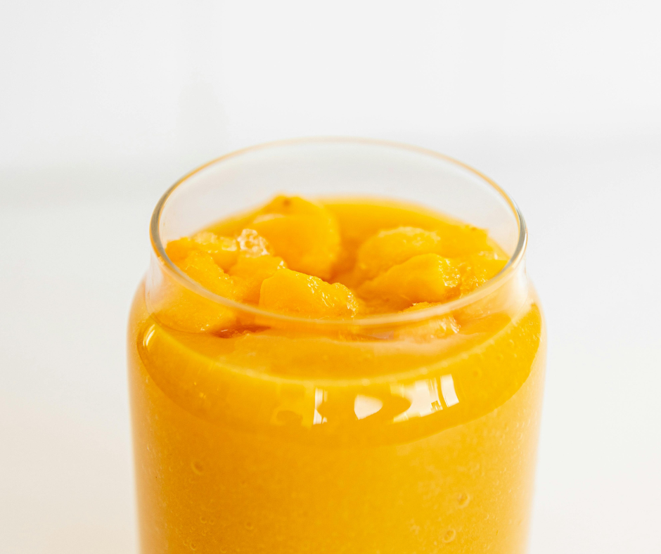 Mango Banana Multivitamin Smoothie in a.clear glass and garnished with mangos