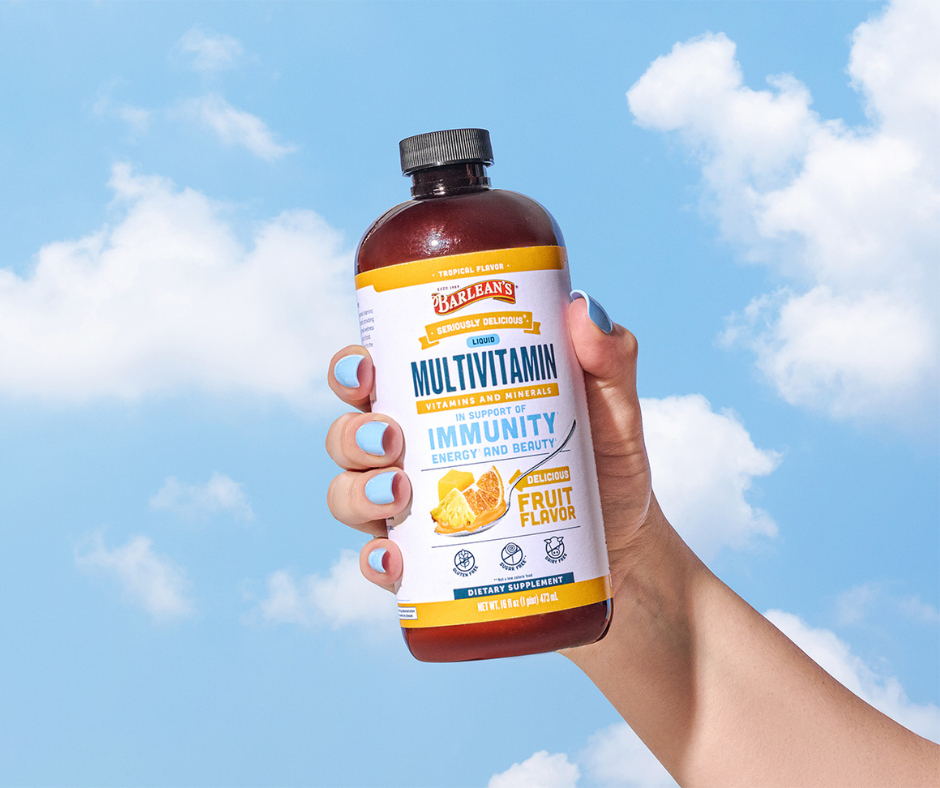 person holding Barlean's tropical liquid multivitamin for immune health, energy, antioxidant support and overall wellness