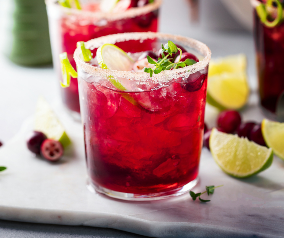 Cherry Citrus Calm Mocktail with lime and cranberries, garnished with fresh herbs and a sugared rim.