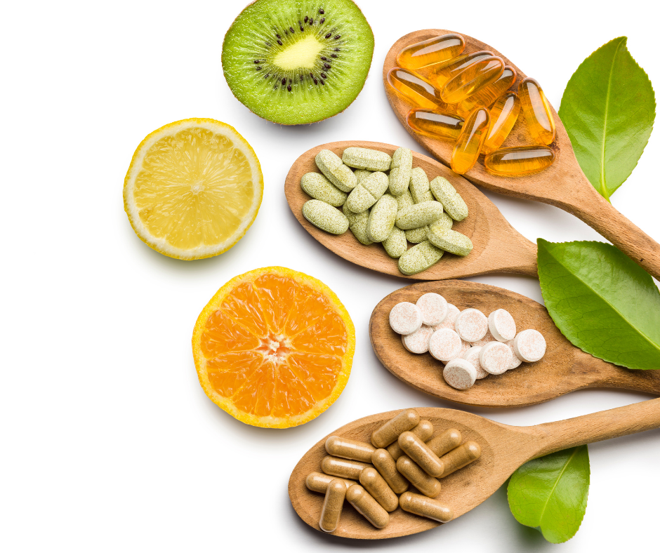 four spoons holding different types of vitamins and pills next to slices of citrus fruit