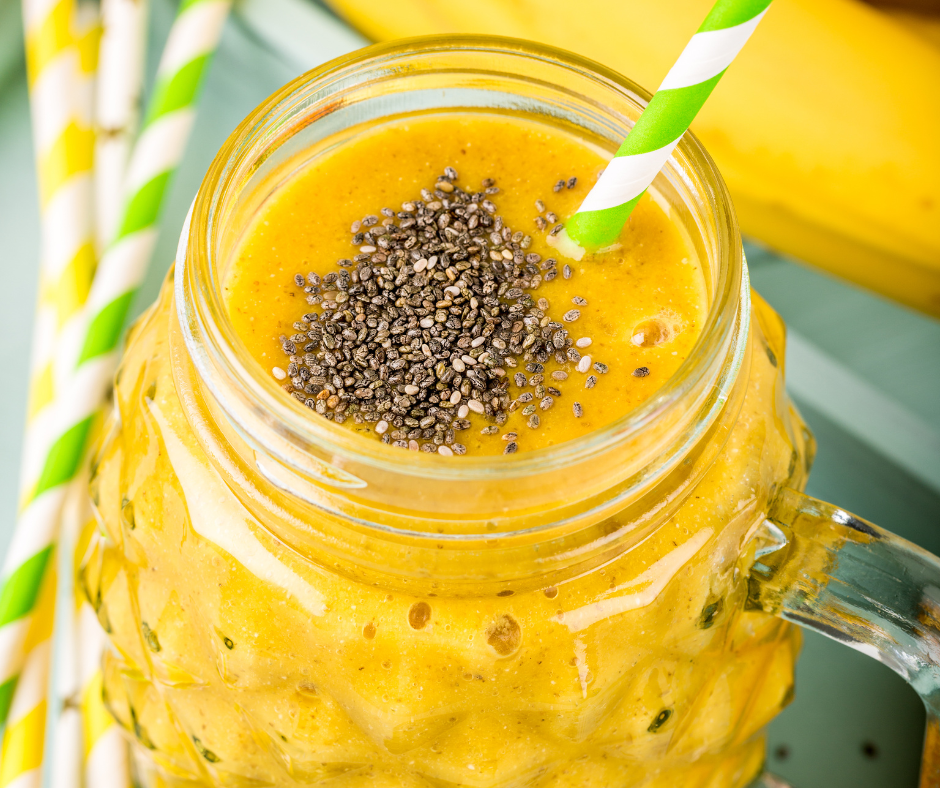Tropical Glow Smoothie Recipe in a glass with fruit and chia seed garnish
