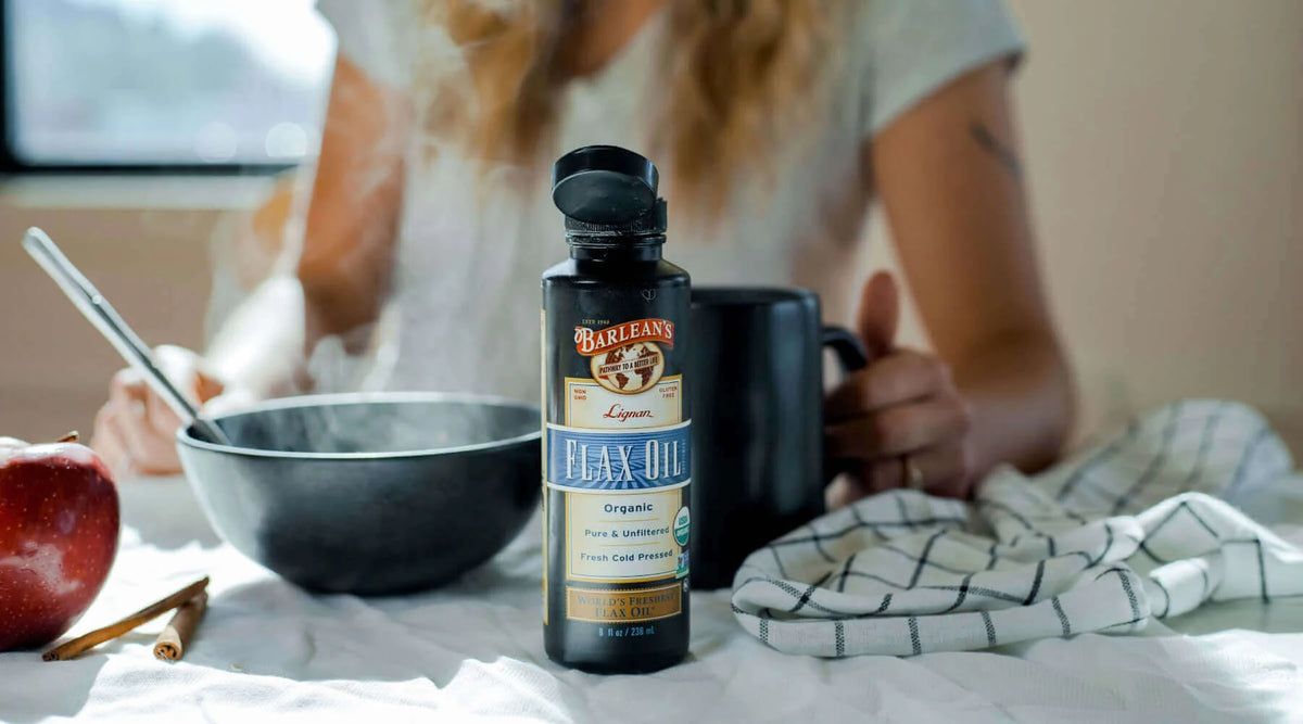 The Truth About Flaxseed Oil and Omega-3s: Bottle of flax oil next to a steaming bowl and apple.