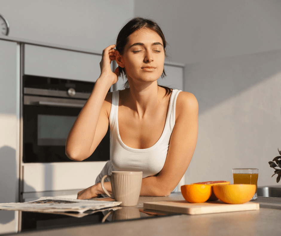 woman waking up in the morning with fruit and a cup of coffee in the kitchen looking peaceful at sunrise