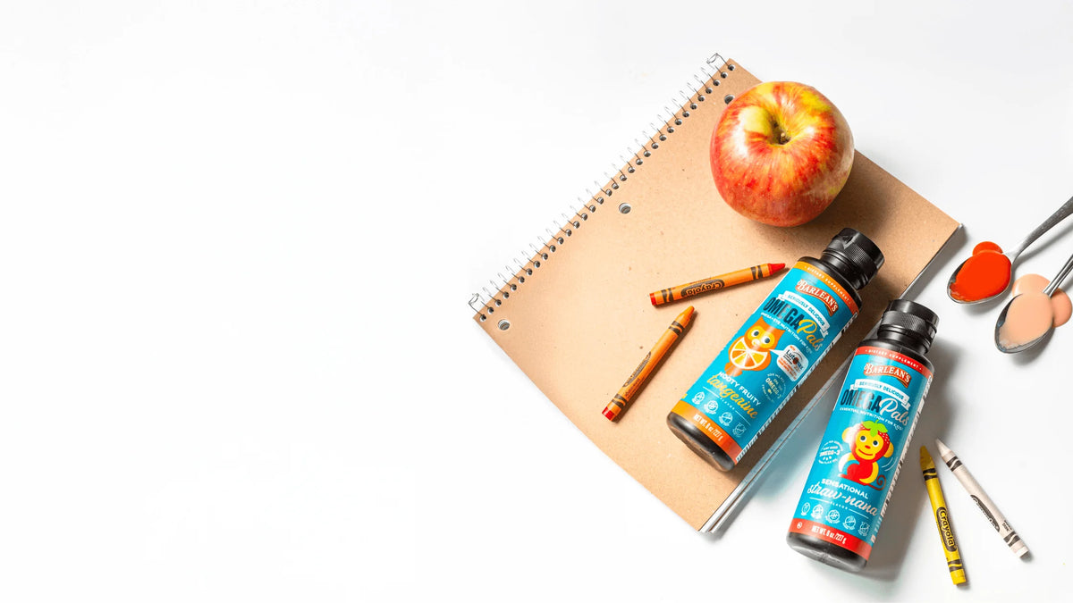 Module 9: Omega Pals (Kids Omega-3 Line) bottles with crayons and an apple on a desk.