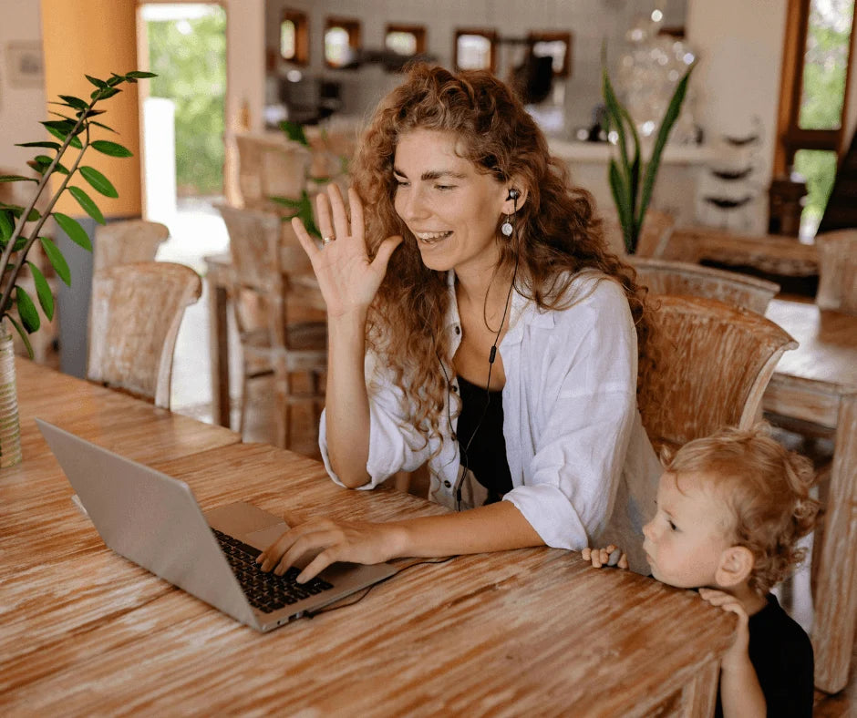 Simple Self-Care Routine for Moms (That Actually Fits a Busy Schedule) - busy mom using laptop with child nearby.