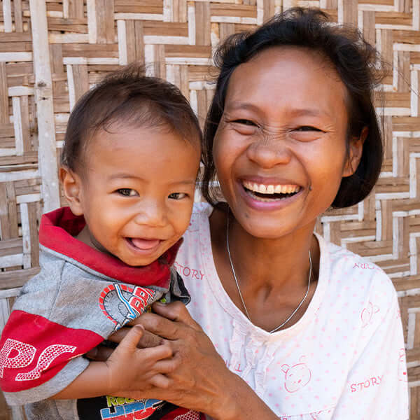 An image of a mother smiling while holding her baby.