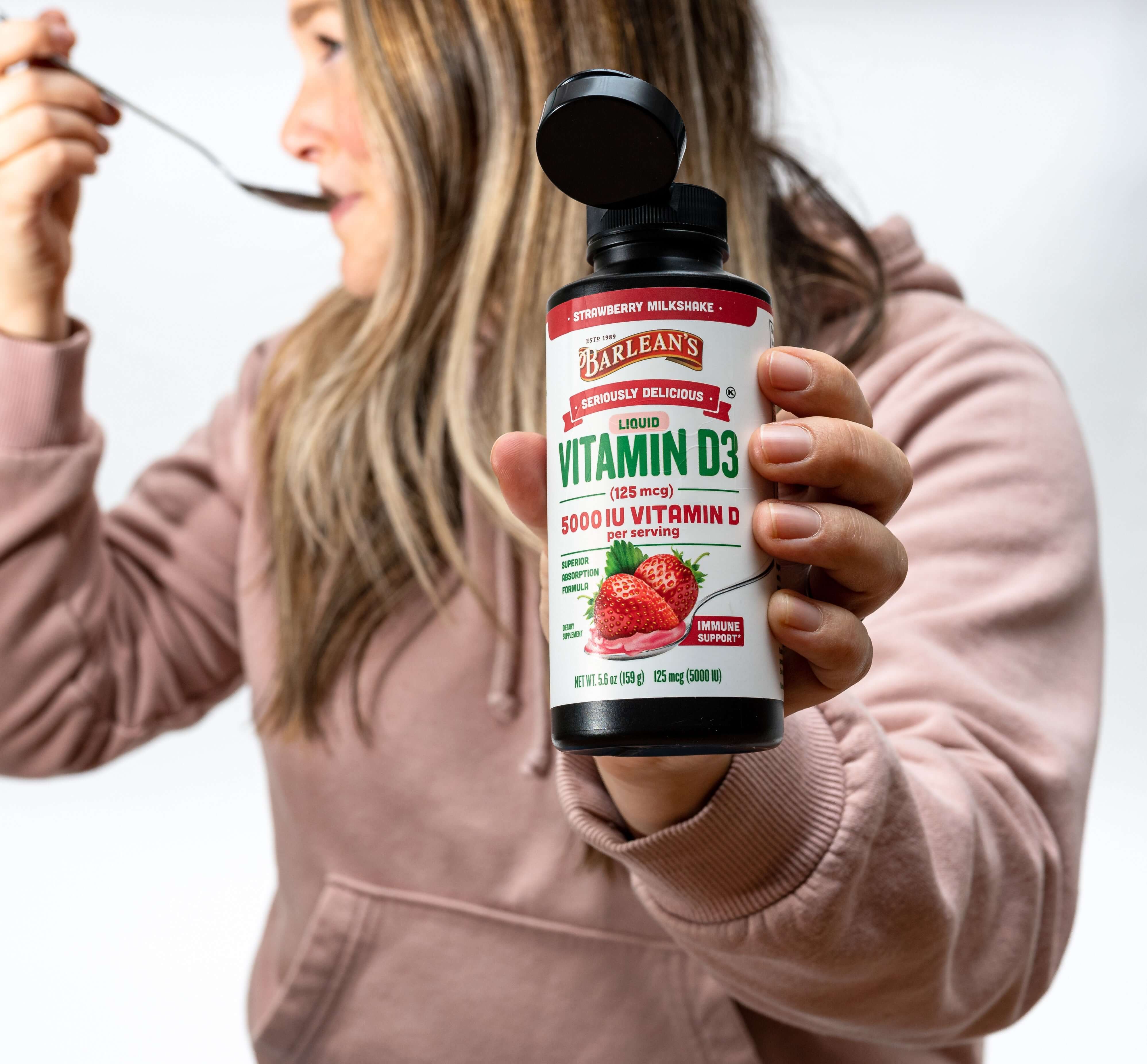 Drinking strawberry vitamin D3 liquid from a spoon