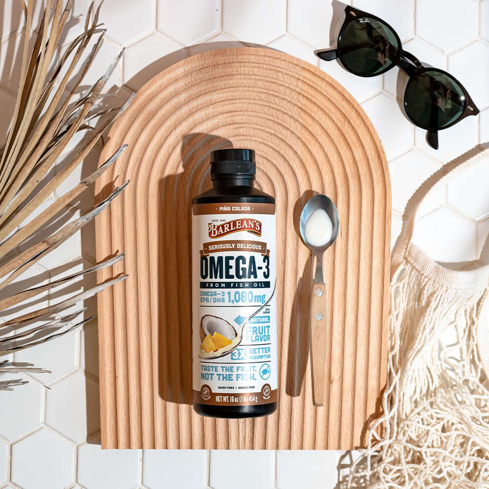 Pina Colada flavored fish oil on a beach with sunglasses and a spoon