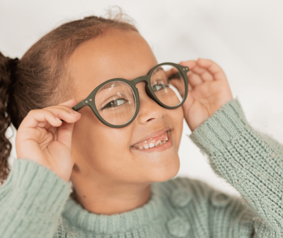 a kid smiling holding their glasses over their eyes