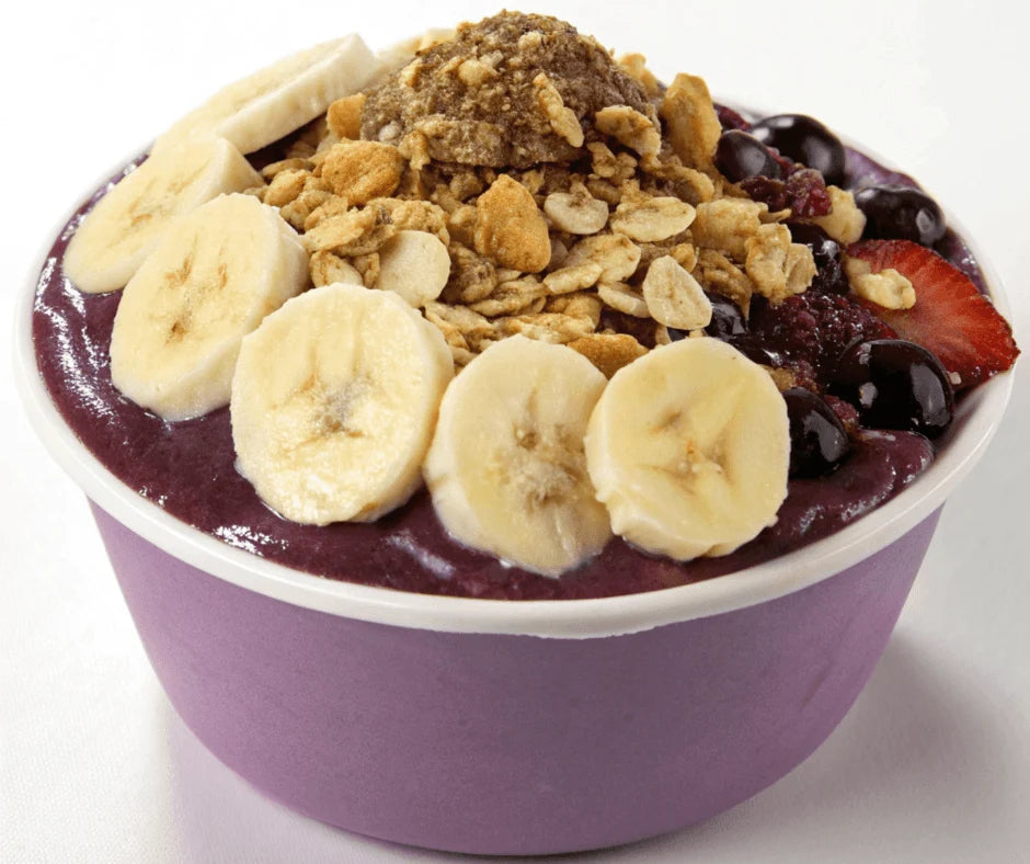 Omega Smoothie Bowl with Berries & Crunchy Toppings topped with banana slices and granola in a purple bowl.