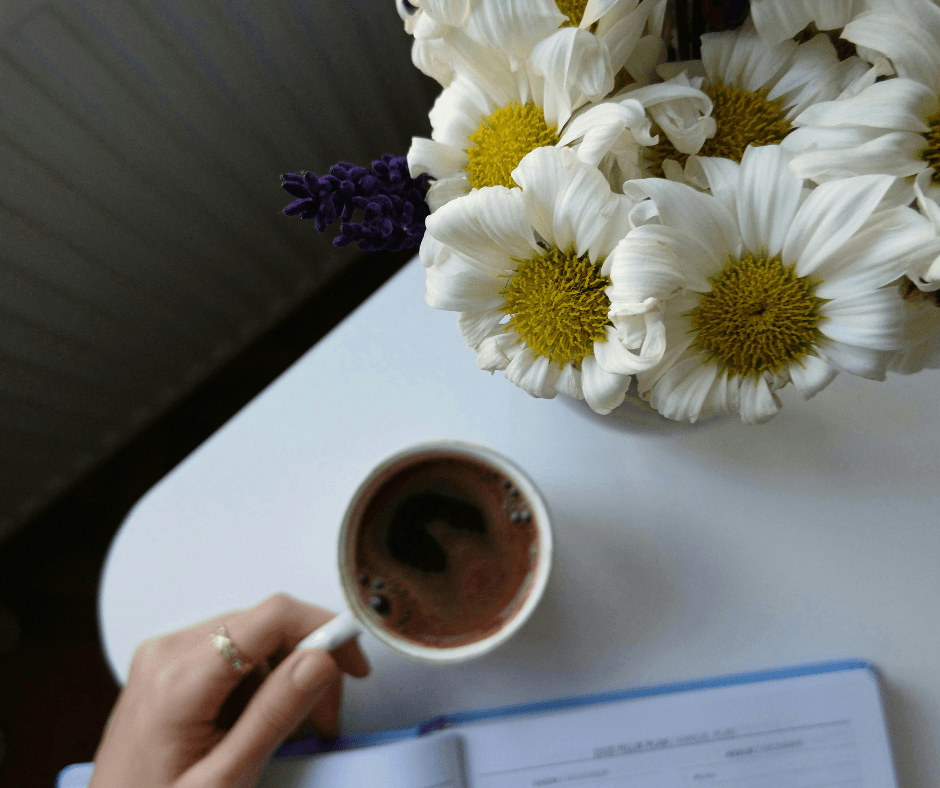 A cup of coffee next to vibrant flowers, promoting relaxation and wellness during Your Spring Wellness Reset: 5 Daily Habits to Feel Lighter & More Energized.