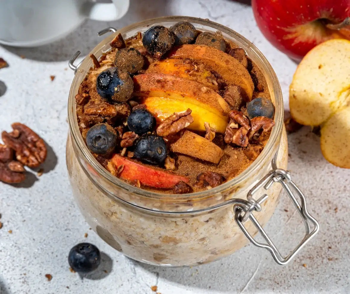 Delicious Apple Cinnamon Overnight Oats with Flax Oil topped with sliced apples, blueberries, and pecans in a jar.