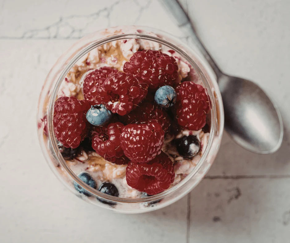 Protein-Packed Overnight Oats with Flax & Almond Butter topped with raspberries and blueberries in a glass jar.