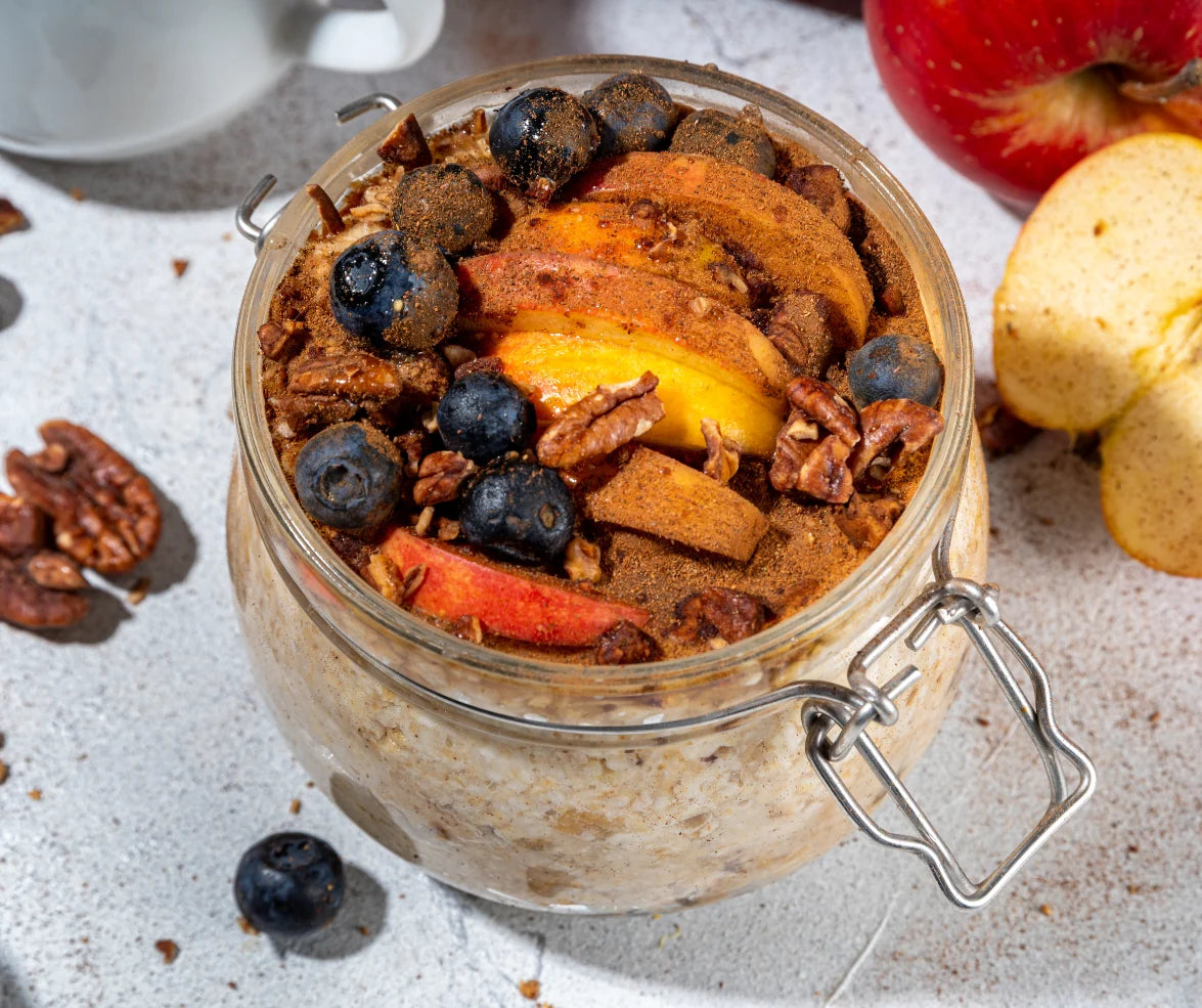 Delicious Apple Cinnamon Overnight Oats with Flax Oil topped with sliced apples, blueberries, and pecans in a jar.