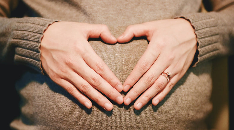 Image: Mom's hands shaped in a heart on her pregnant belly