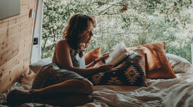 Image: Woman relaxing in back of van while reading book