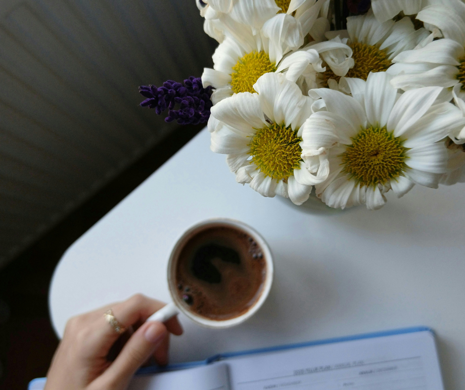 A cup of coffee next to vibrant flowers, promoting relaxation and wellness during Your Spring Wellness Reset: 5 Daily Habits to Feel Lighter & More Energized.