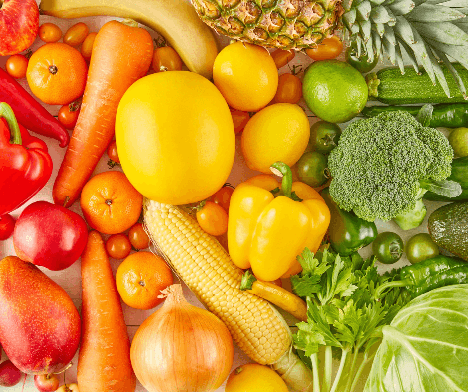 red, orange, green, and yellow fruits and vegetables displayed on a white countertop