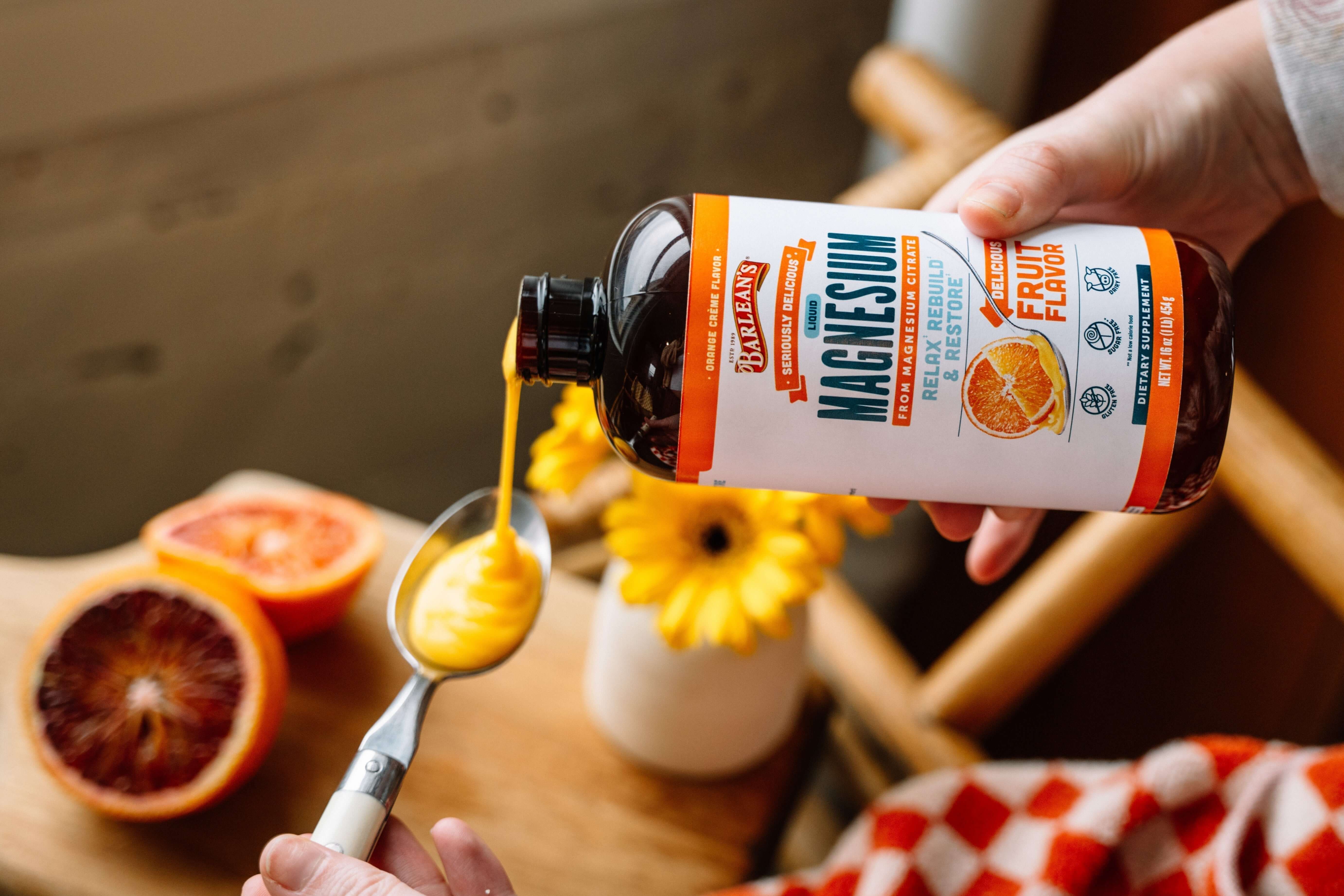 A person pouring liquid magnesium from a bottle, showcasing magnesium benefits for health with fresh fruits in the scene.