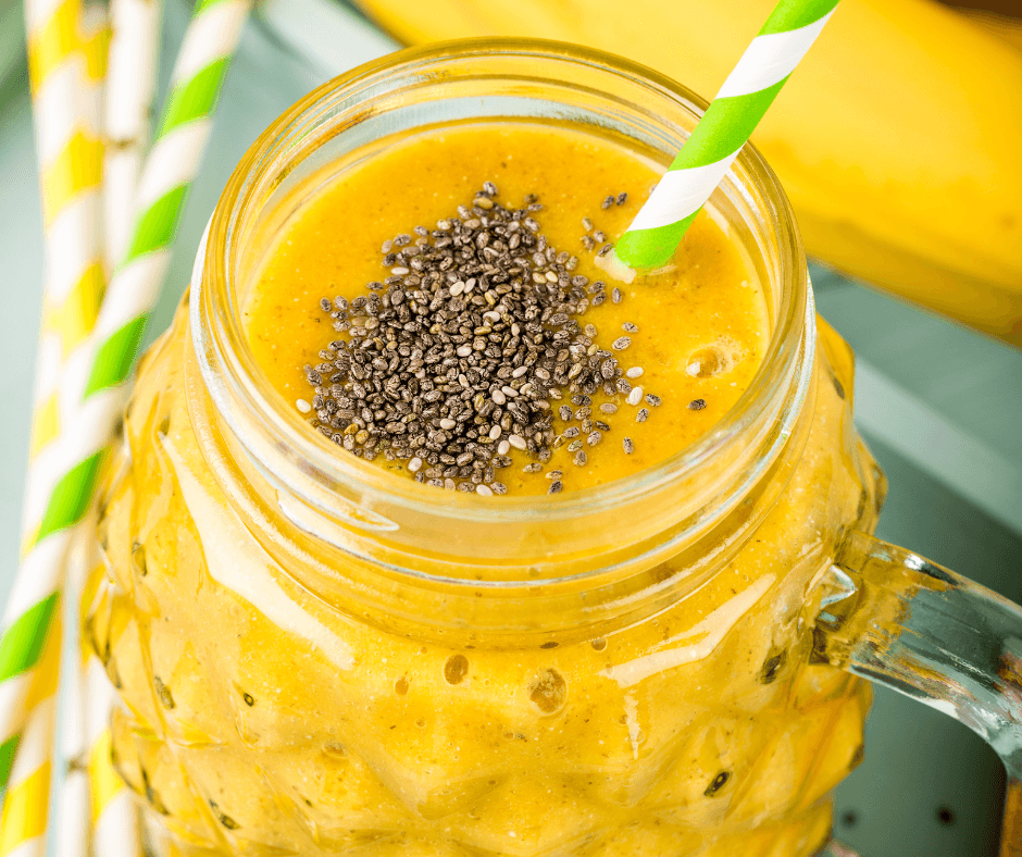 Tropical Glow Smoothie Recipe in a glass with fruit and chia seed garnish