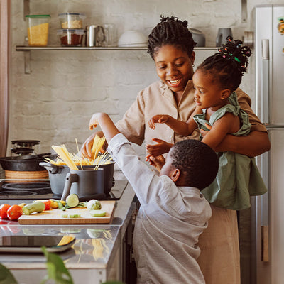 A mother making dinner with her 2 children.