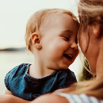 A baby smiling at its mother.