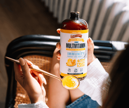 Picture of Barlean's Tropical Liquid Multivitamin at home next to a spoon filled with the creamy multivitamin